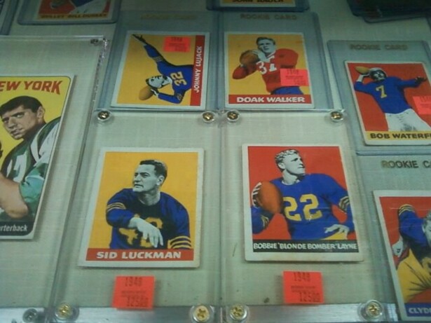 Image description: trading cards featuring white football players in plastic holders fill a display case.