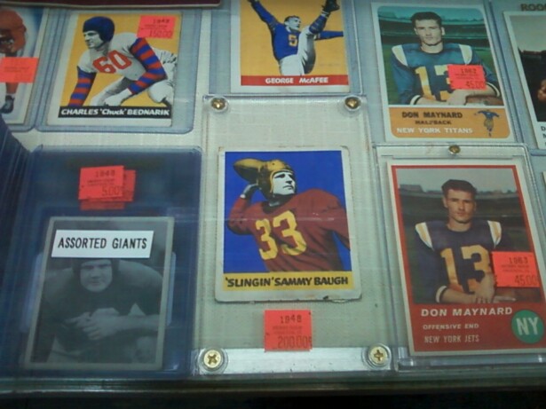 Image description: trading cards featuring white football players in plastic holders fill a display case. 