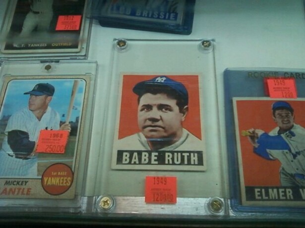 Image description: baseball cards featuring white baseball players in plastic holders fill a display case.