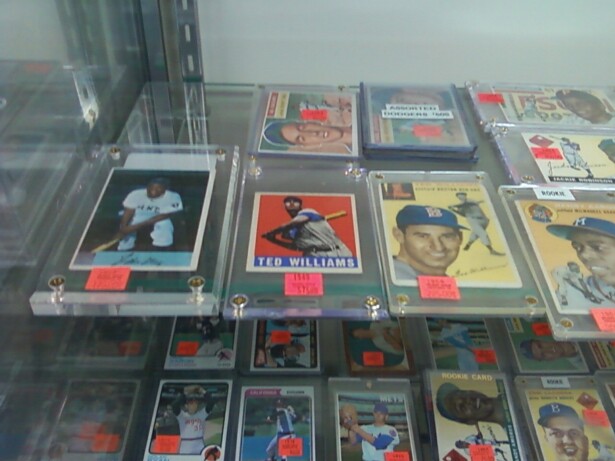 Image description: baseball cards featuring white and black baseball players in plastic holders fill a display case.