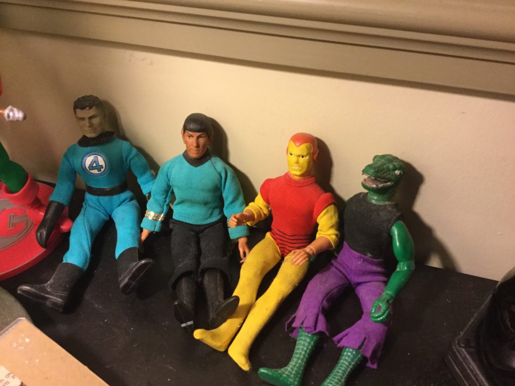 Mego's World's Greatest Super-Heroes and Star Trek figures sit on a desk. From left to right, Mr. Fantastic, Mr. Spock, Iron Man and The Lizard.