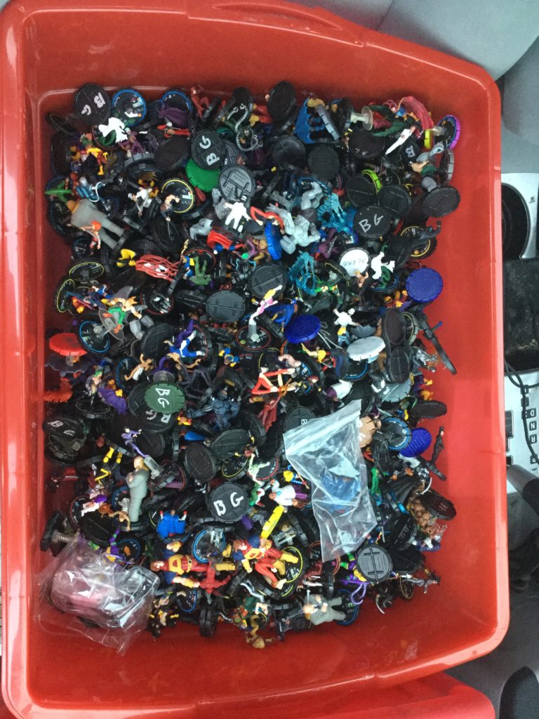 A red bin filled with hundreds of Heroclix super-hero game figurines.