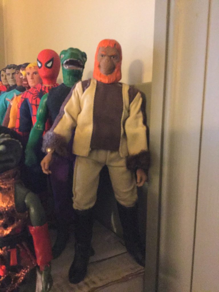 Mego 8" action figures. Top row: Planet of the Apes character Dr. Zaius, humanoid orangutan with orange hair in beige and brown outfit in front, with a number of other figures behind and next to him.