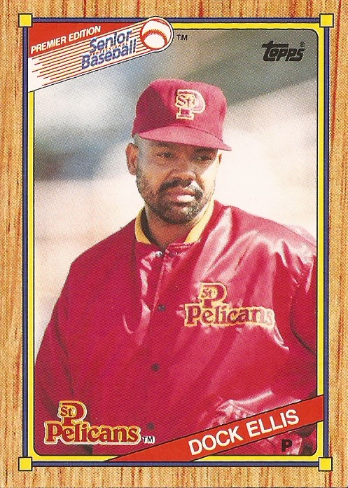 1989-1990 Topps Senior League baseball card of Dock Ellis, pictured in the center of the card, a man with brown skin and a black beard, wearing a red St. Petersburg Pelicans hat and warm-up jacket. Card has a woodgrain border, and logos from Senior League Baseball at top left, Topps at top right, and the St. Petersburg Pelicans at bottom left, with Docks name and abbreviation for his position, P for pitcher, at bottom right.