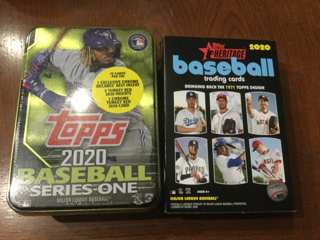 tin of 2020 Topps Series One baseball cards, and hanger box of 2020 Topps Heritage baseball cards on a brown table